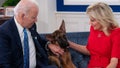 US President Joe Biden and US First Lady Jill Biden, look at their new dog Commander, after speaking virtually with military service members to thank them for their service and wish them a Merry Christmas, from the South Court Auditorium of the White House in Washington, DC, on December 25, 2021.