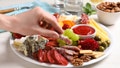 Woman taking sausage from plate with different appetizers on white wooden table, closeup - Fox News