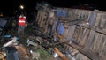 People stand near the wreckage of vehicles after a fatal accident in Londiani, Kenya early Saturday, July 1, 2023, at a location known for crashes about 200 kilometers (125 miles) northwest of the capital, Nairobi. Dozens were killed when a truck rammed into several other vehicles and market traders on Friday evening, police said. (AP Photo)