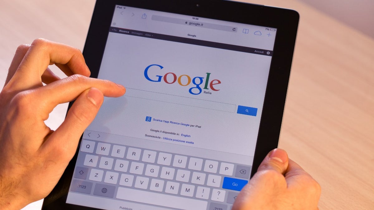 A person is holding their iPad with a Google search page on the screen