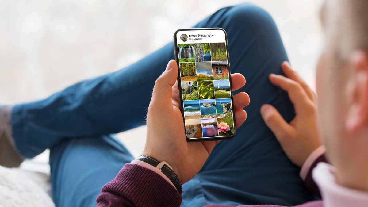 Photo of a man holding up his phone, looking at his photos.