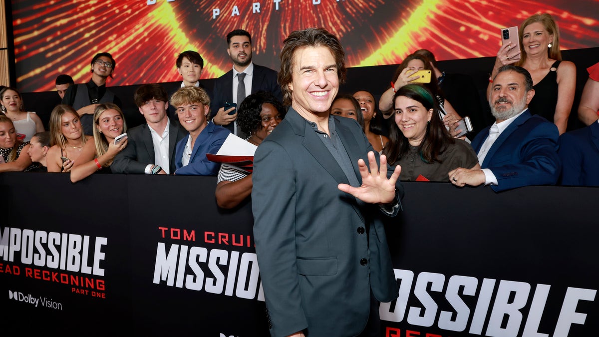 Tom Cruise stands in front of fans and waves