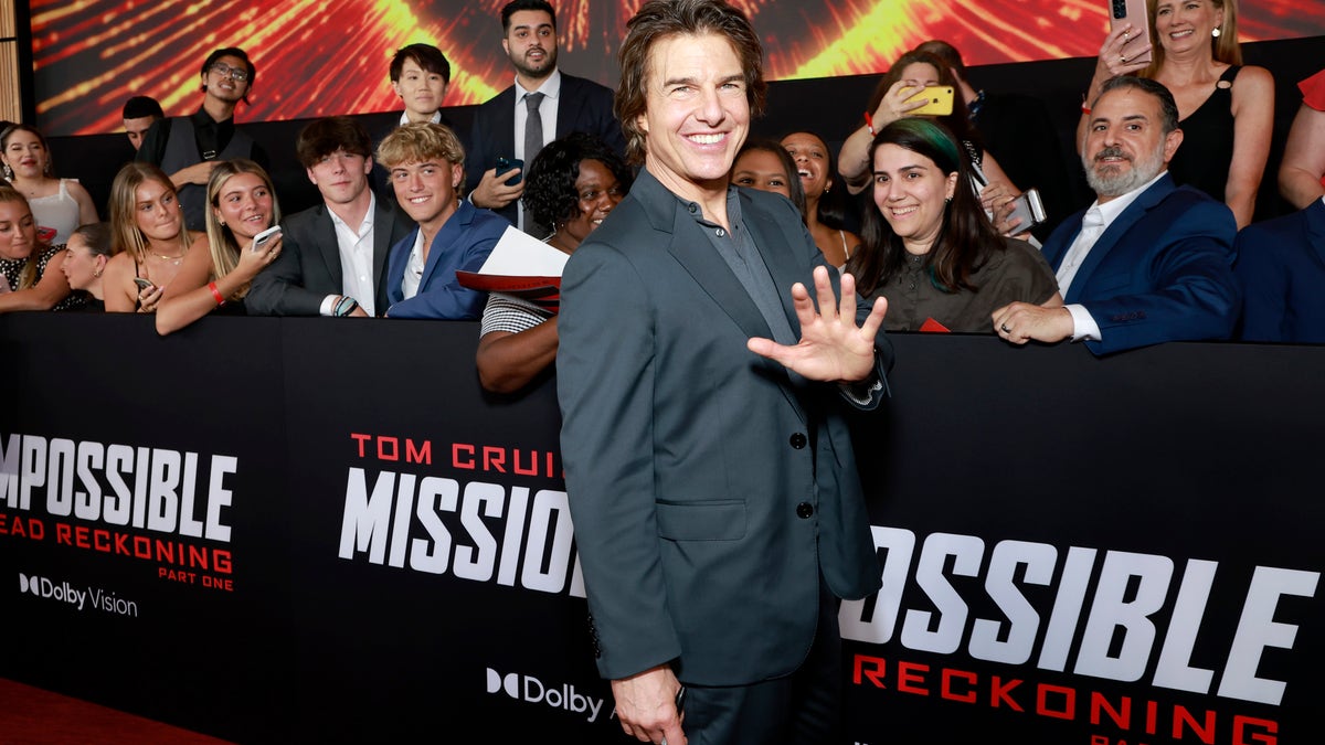 Tom Cruise stands in front of fans and waves