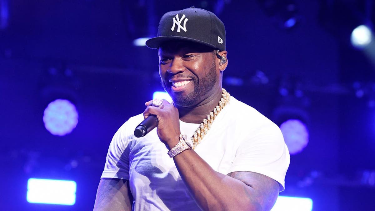 50 Cent wearing Yankees cap, holding microphone
