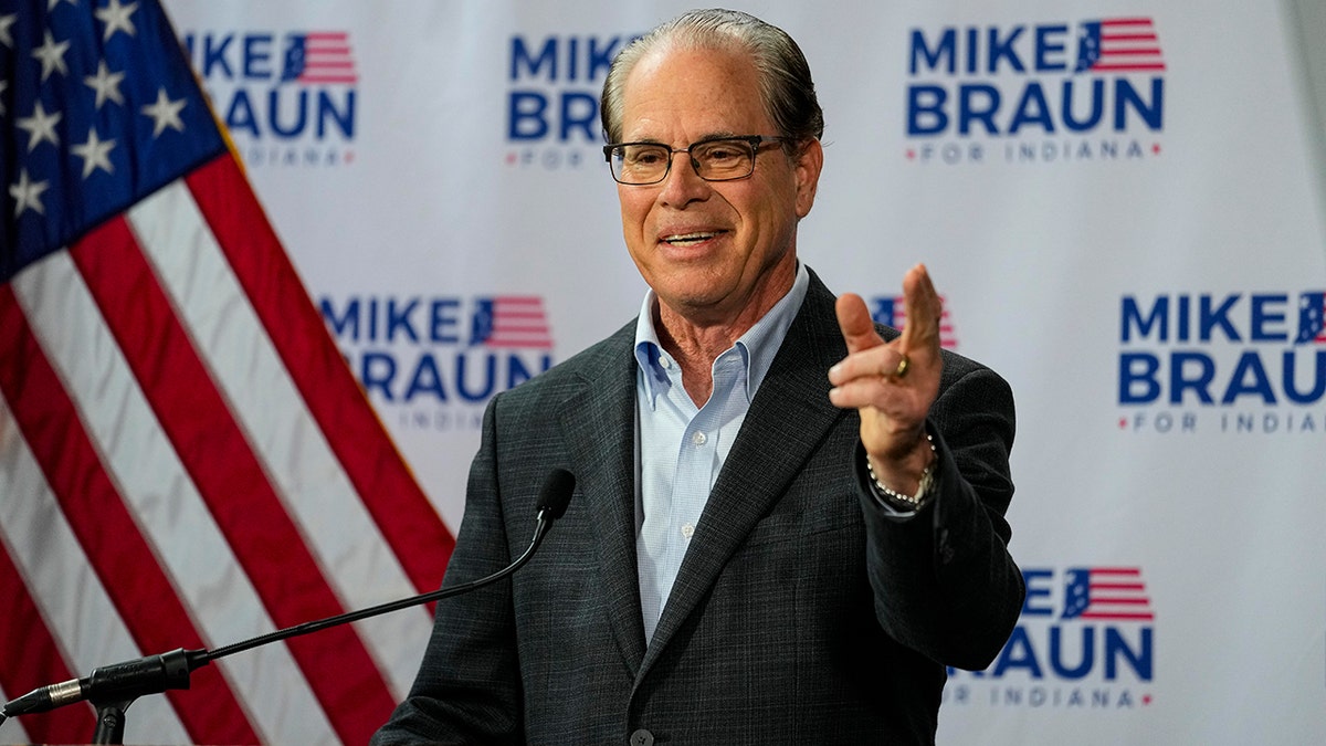 Sen. Mike Braun, gesturing with near  manus  successful  beforehand   of flag, run  backdrop