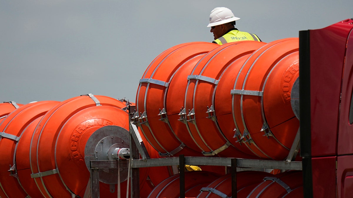 A worker helps unload large buoys that are set to be deployed in the Rio Grande, Friday, July 7, 2023, in Eagle Pass, Texas, where border crossings continue to place stress on local resources. Advocates have raised concern that the barriers may have an adverse environmental impact. (AP Photo/Eric Gay)