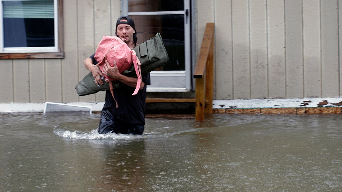 A man carries belongings through floodwaters