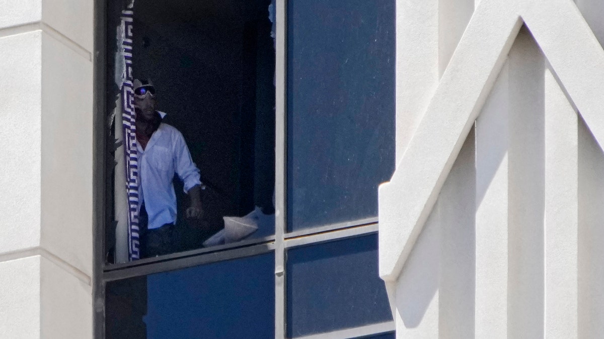 Person looking out broken window at Caesars Palace