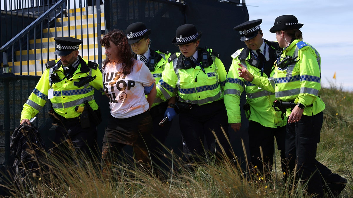 A "Just Stop Oil" protester is led away by police near the 17th hole during the second day of the Open Championships at the Royal Liverpool Golf Club in Hoylake, England, on July 21, 2023.