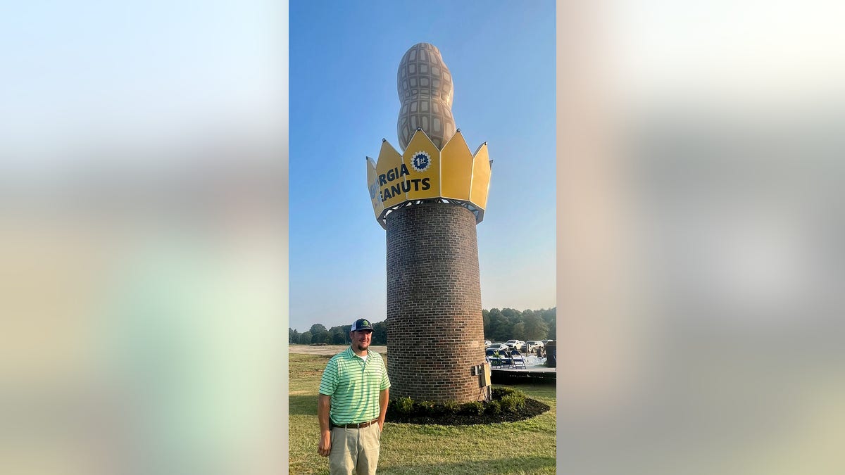Man standing in front of giant peanut