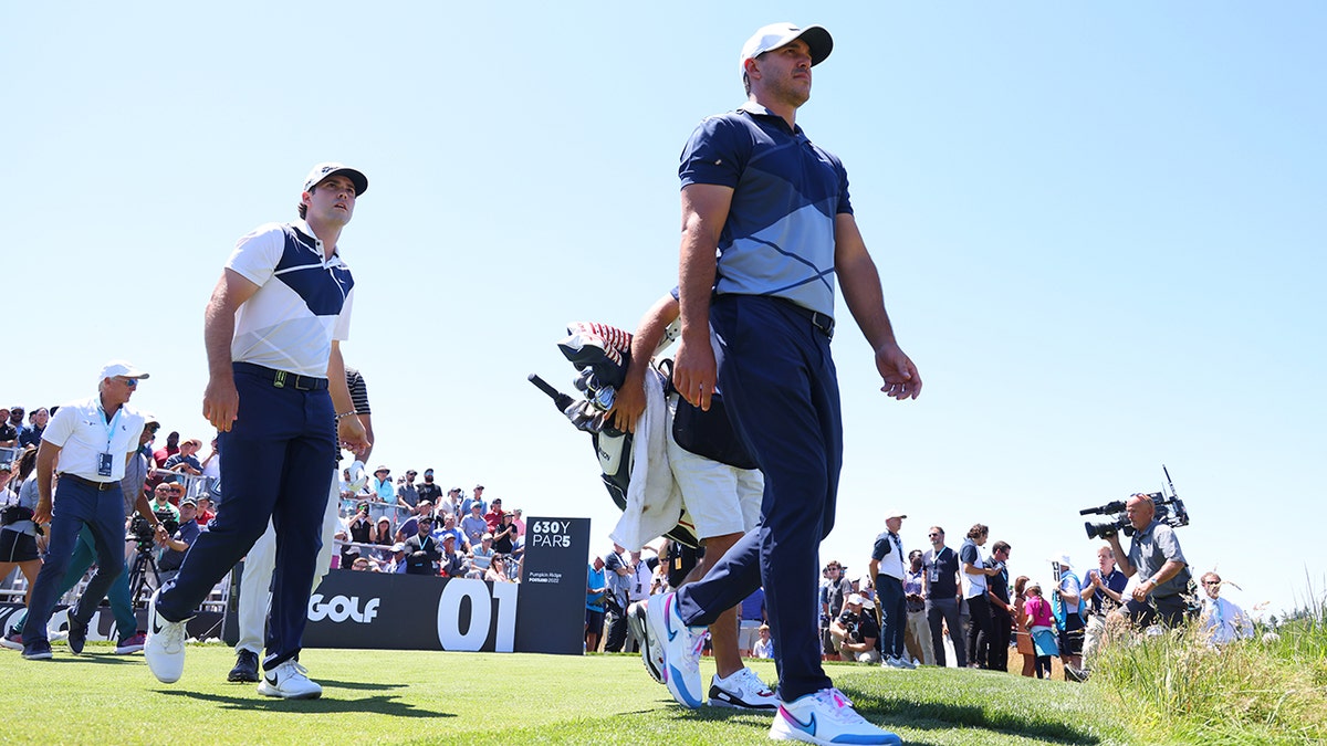 Brooks Koepka and Matt Wolff walk off the first tee