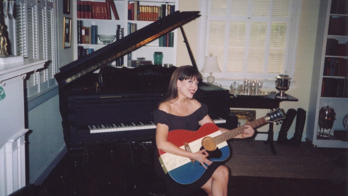 Victoria Hallman holding a guitar with the shades red, white and blue