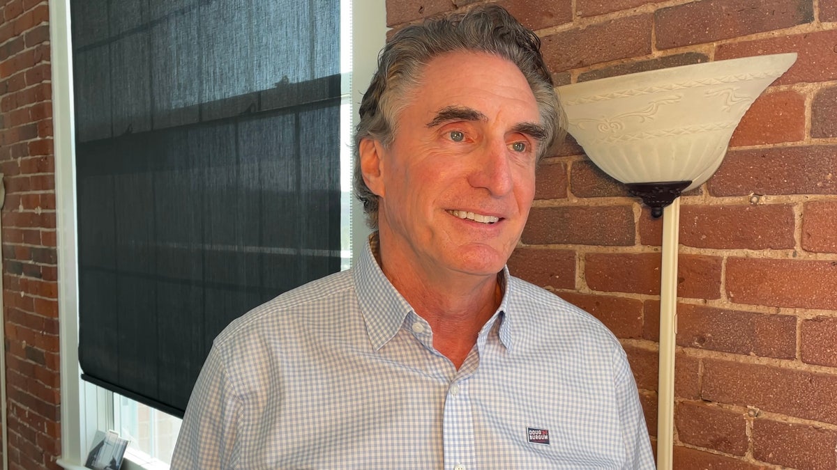 Doug Burgum in button down shirt by brick wall