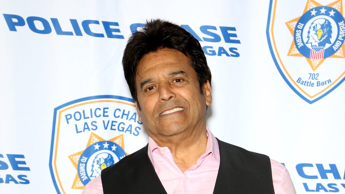 Erik Estrada smiling in front of police signage