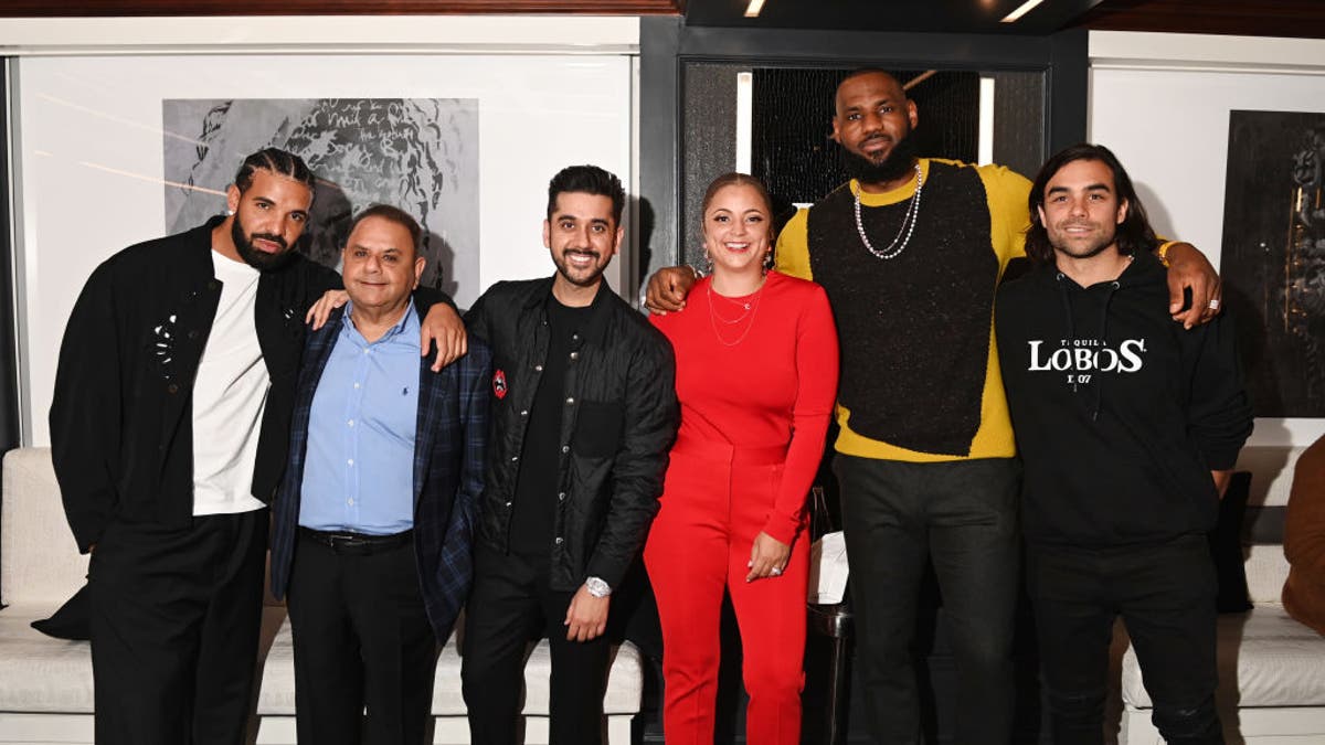 Erin Harris wears a red pantsuit and poses with Drake and LeBron James.