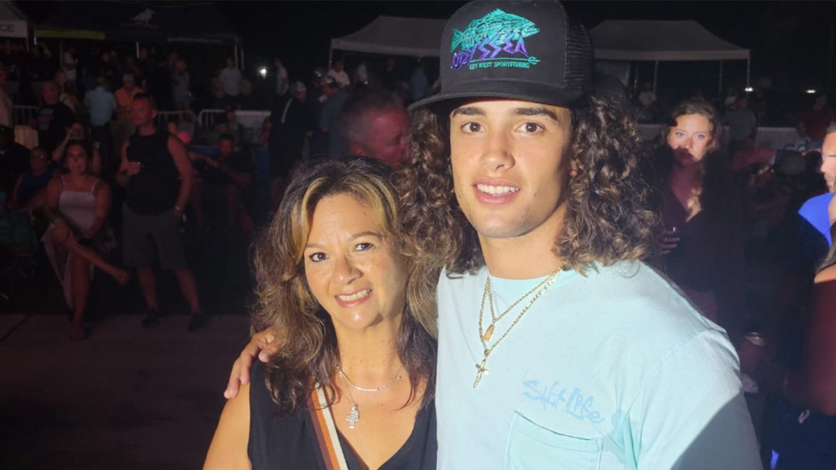 Florida man in black baseball cap puts his arm around his mom's shoulder.