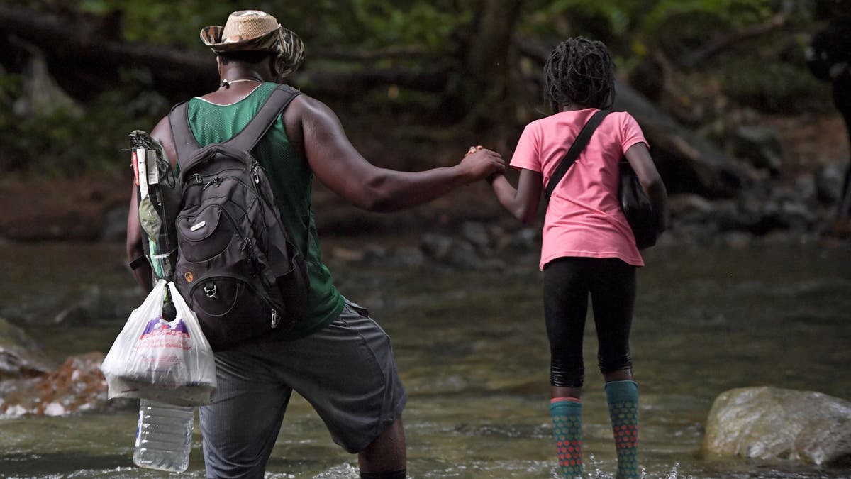 A Haitian migrant man holds a girl's hand as they cross the jungle of the Darien Gap, near Acandi, Choco department, Colombia, heading to Panama, on September 26, 2021, on their way trying to reach the U.S.