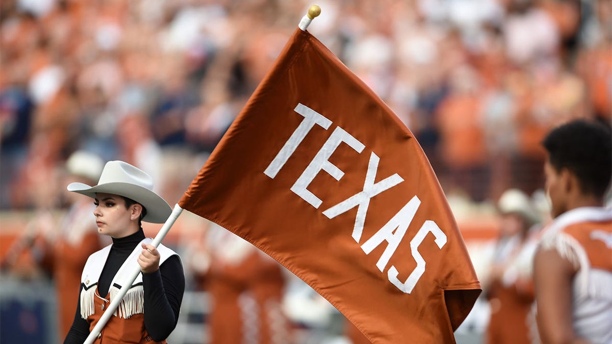 A Texas band member carries the Longhorns flag
