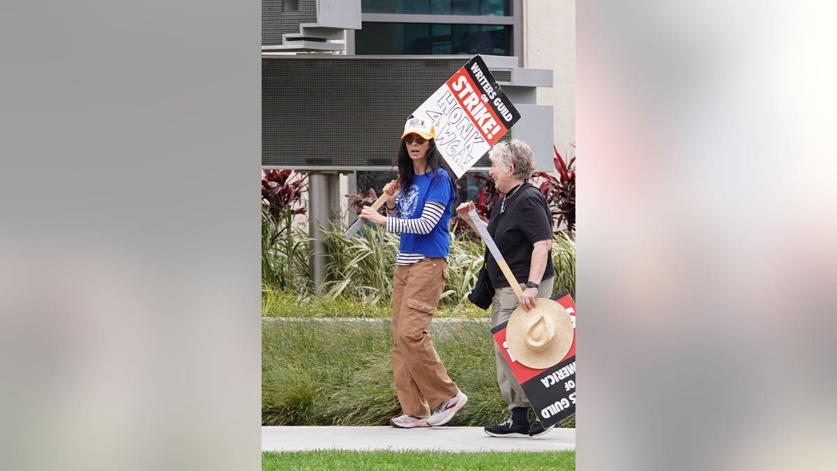 Sarah Silverman at a Writers Gild strike carrying a sign.