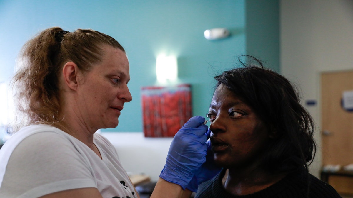 Nurse Michelle Absher (left) administers medicine to Breanna Blueford's eye at the Dore Urgent Care clinic, which is a crisis drop-in center for mental health needs in San Francisco, on June 10, 2019.