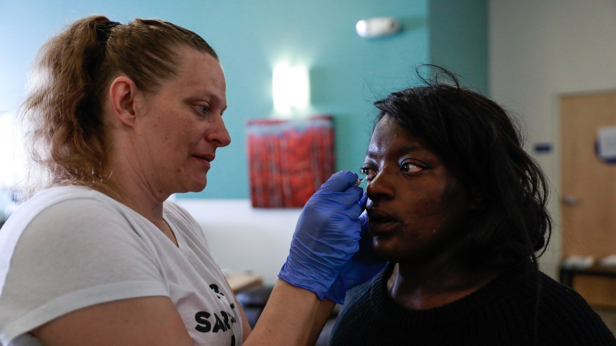 Nurse Michelle Absher (left) administers medicine to Breanna Blueford's eye at the Dore Urgent Care clinic, which is a crisis drop-in center for mental health needs in San Francisco, on June 10, 2019.