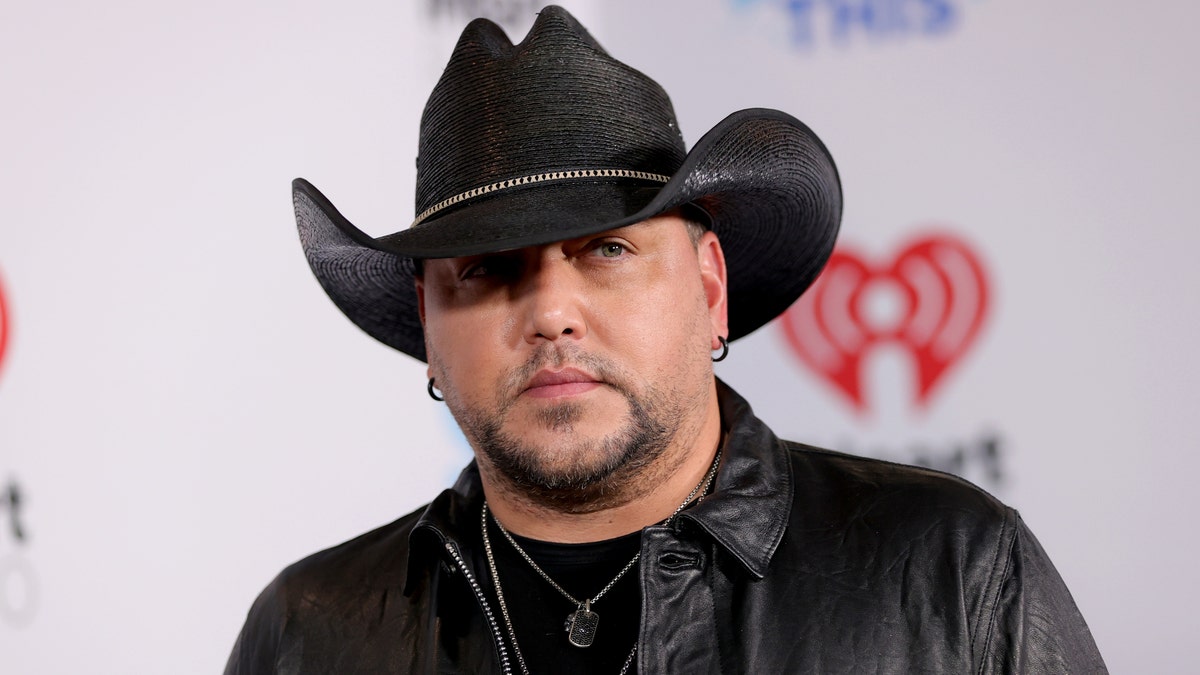 Jason Aldean looks off in the distance wearing a black cowboy hat