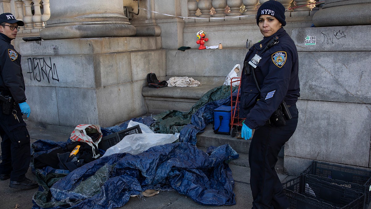 NYPD officer removes debris from homeless camp
