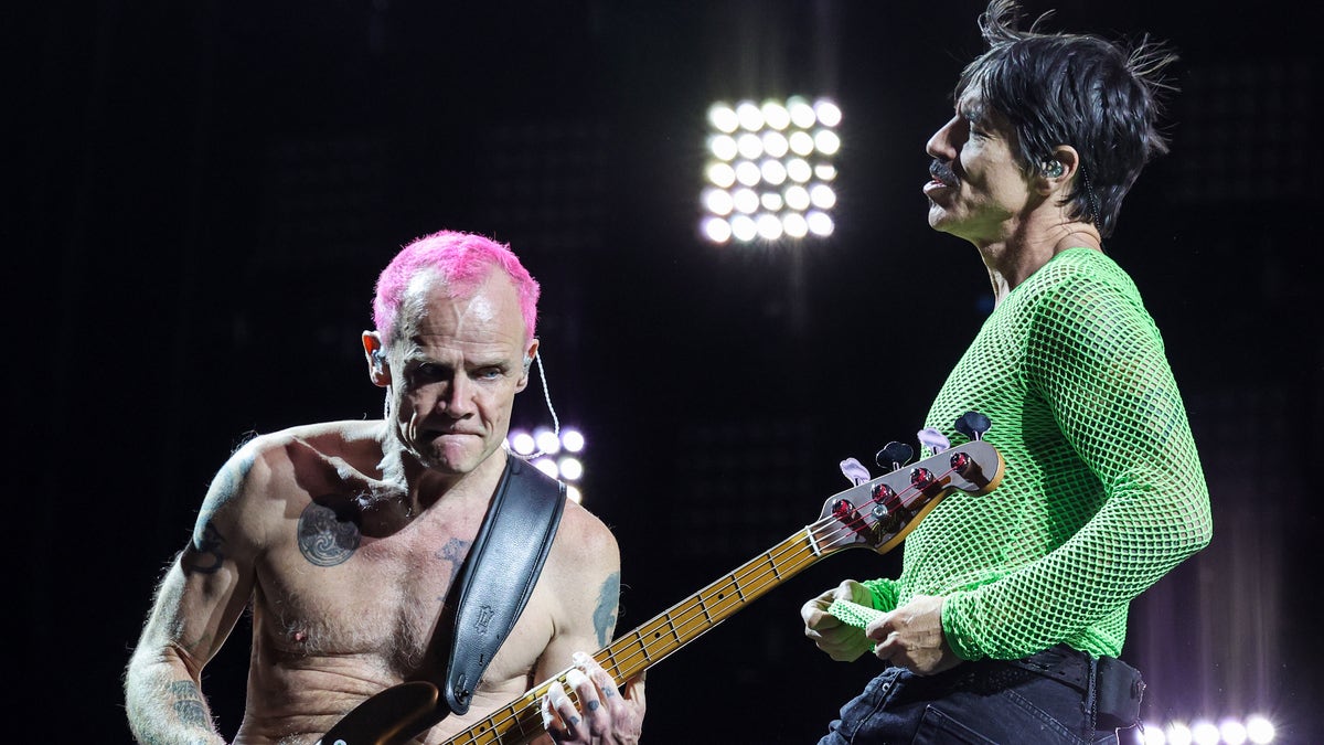 Flea plays bass with pink hair while onstage with Anthony Kiedis