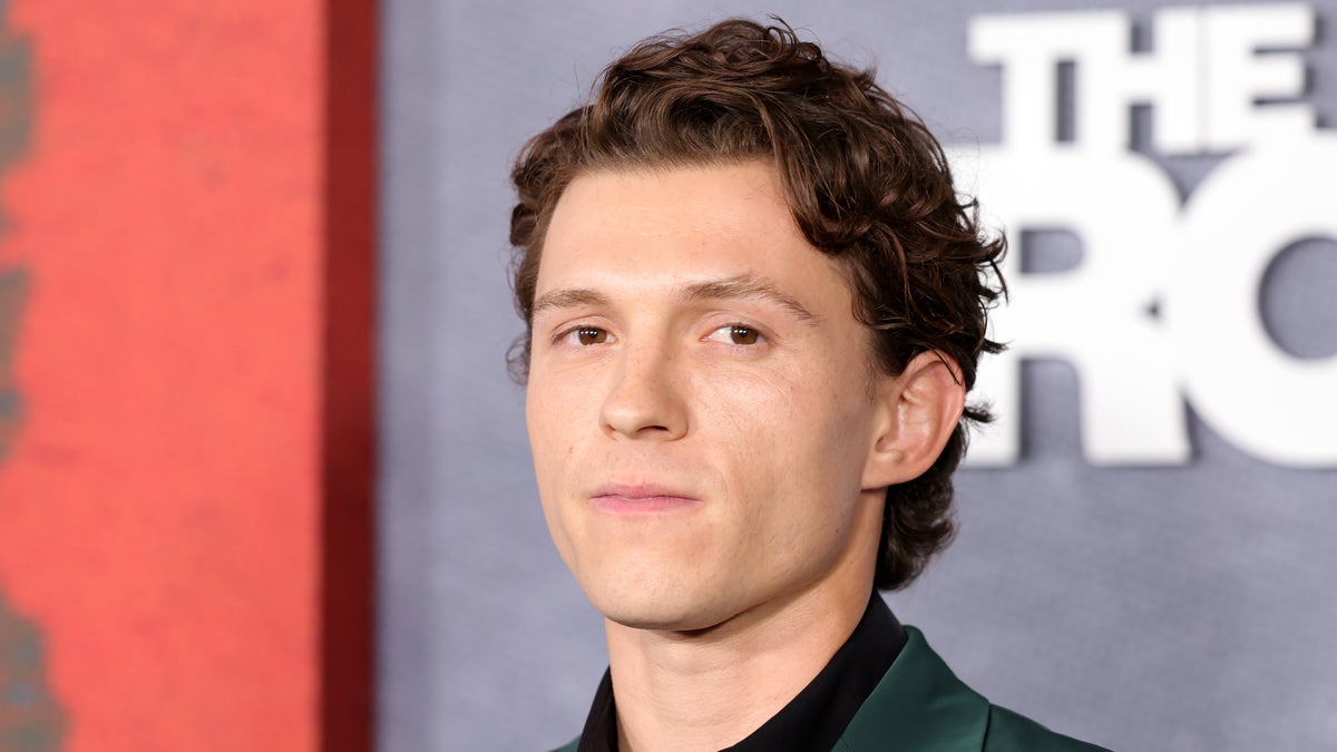 Tom Holland looking serious in a green suit