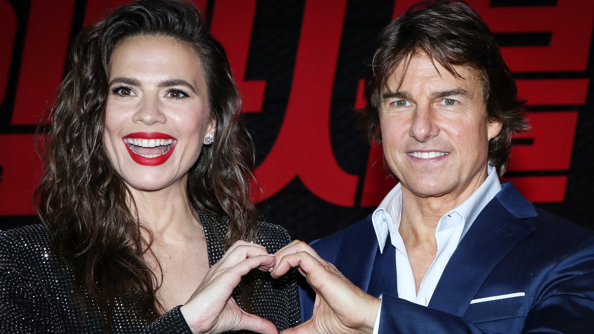 Tom Cruise and Haylet Atwell form a heart with their hands 