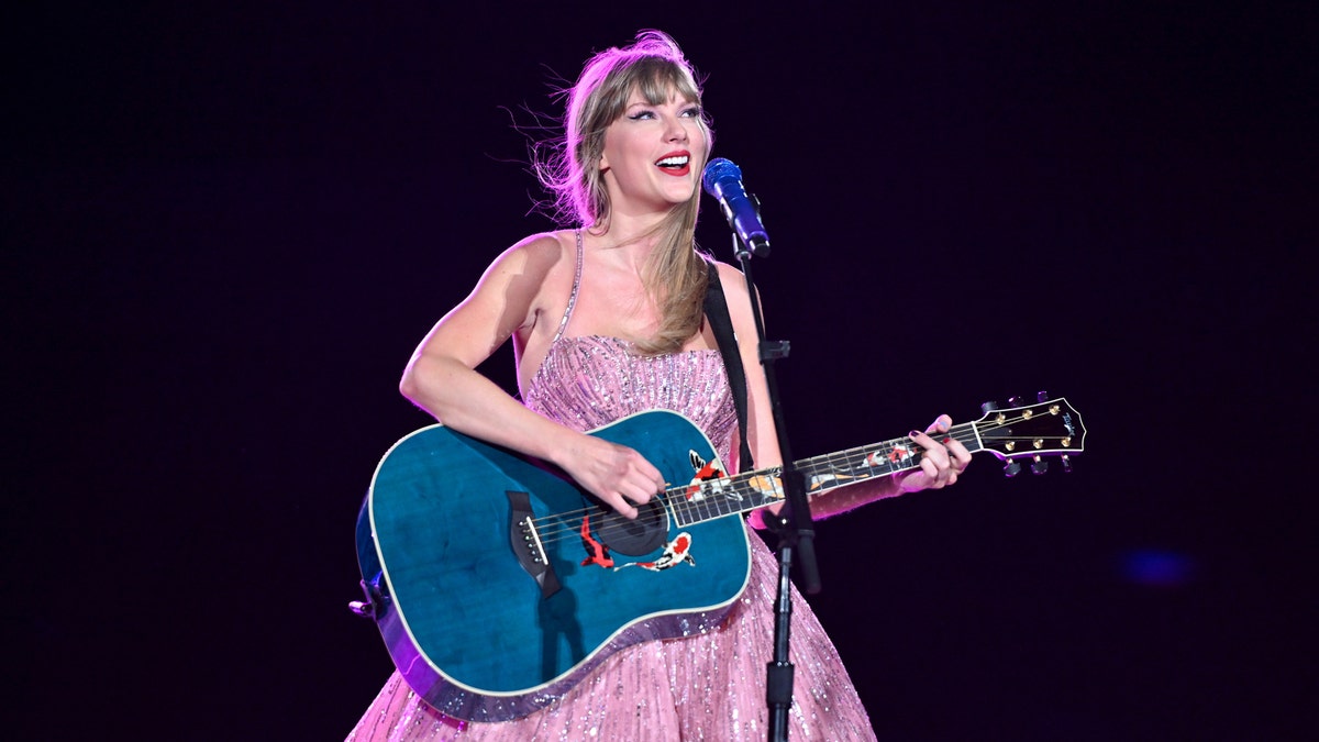 Taylor Swift in her purple dress and blue guitar playing in Denver on the Eras Tour