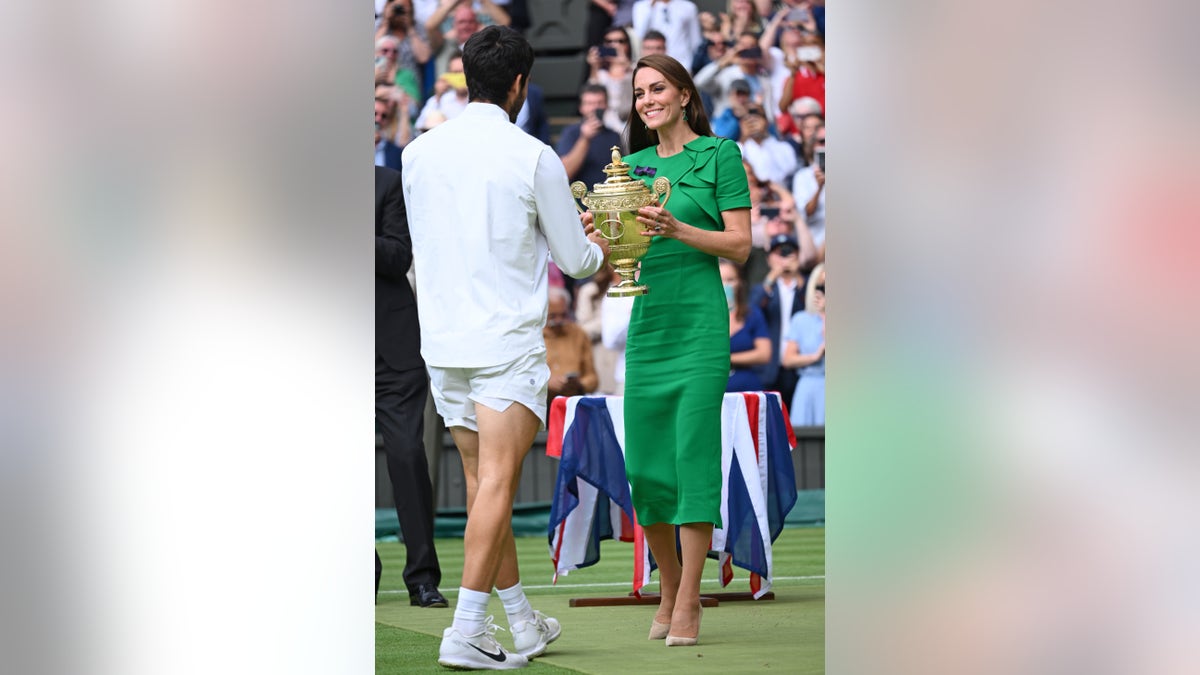 Kate Middleton wearing a green dress presents the Wimbledon trophy to Carlos Alcaraz Garfia