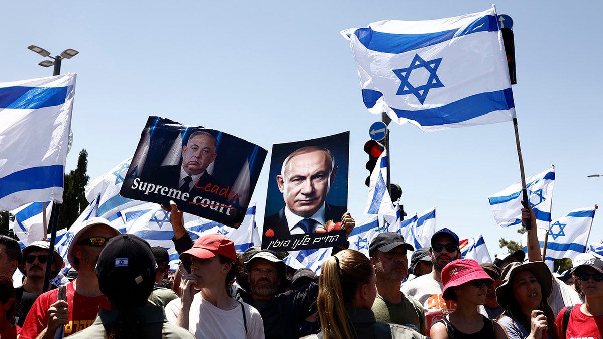 Protesters hold a Netanyahu poster