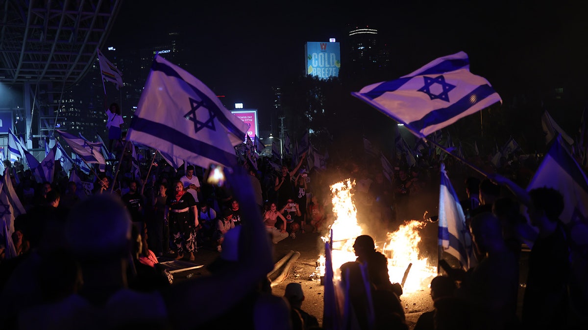 Protesters wave Israeli flags, light fire in the street
