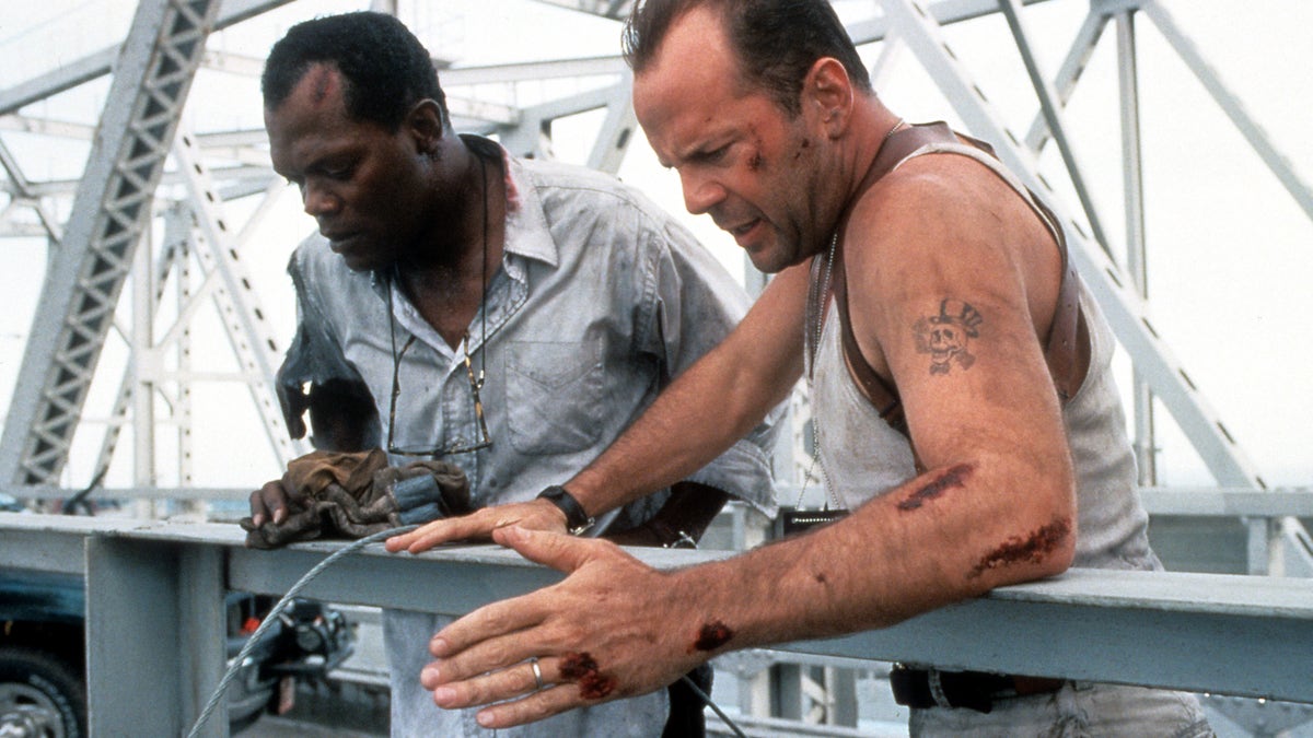 Samuel L Jackson and Bruce Willis standing on a bridge, looking down in a scene from the film Die Hard: With a Vengeance