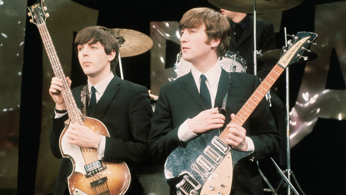 Paul McCartney and John Lennon hold their guitars on The Ed Sullivan Show