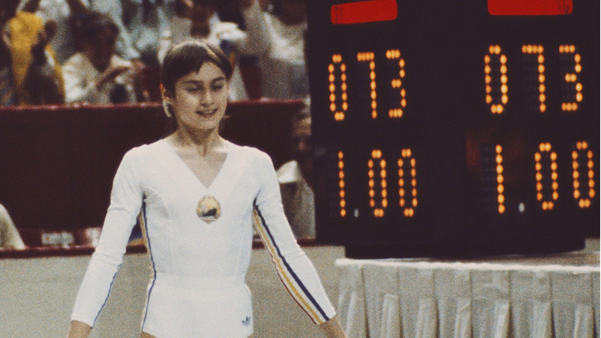 Nadia stands next to the scoreboard that marks 1.00