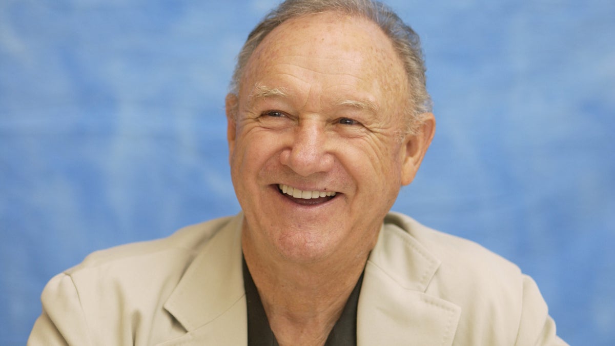 Gene Hackman smiling wearing a tan suit