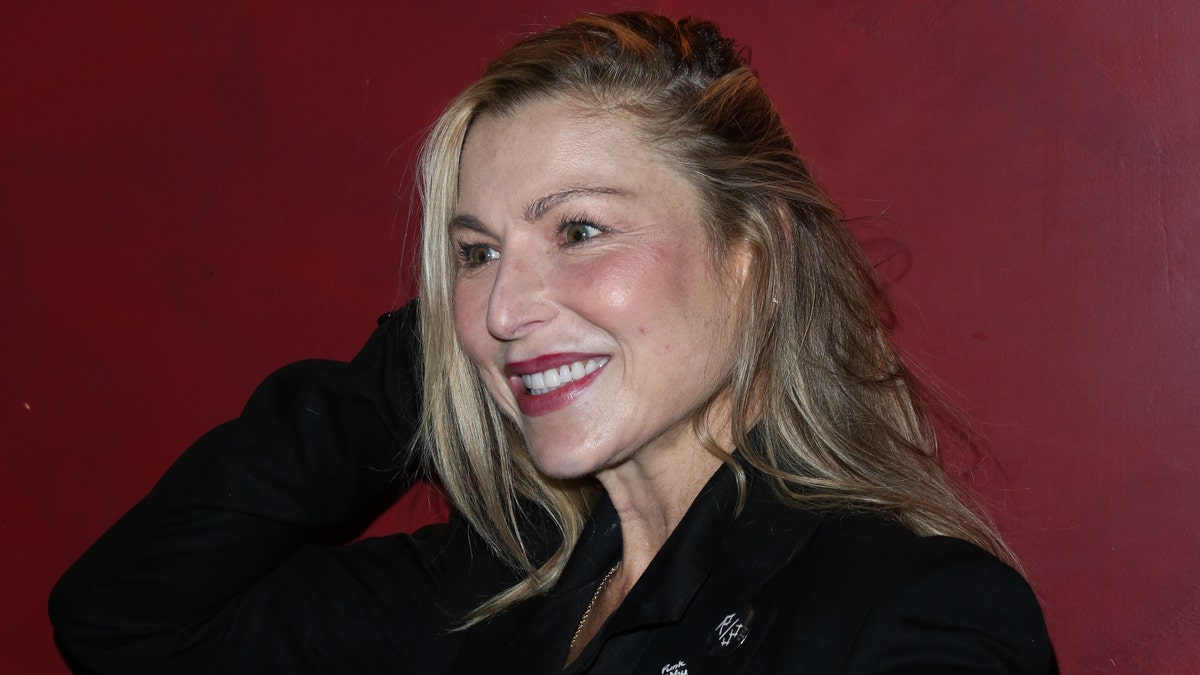 Tatum O'Neal wearing a black suit and smiling.