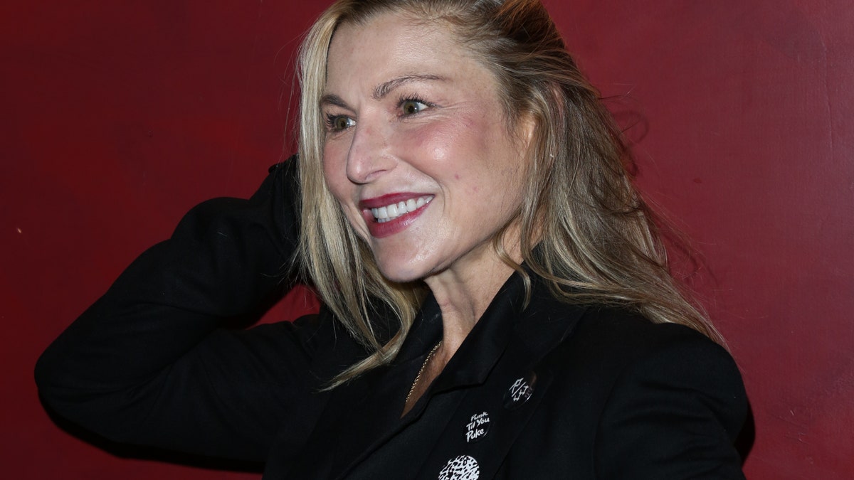 Tatum O'Neal wearing a black suit and smiling.