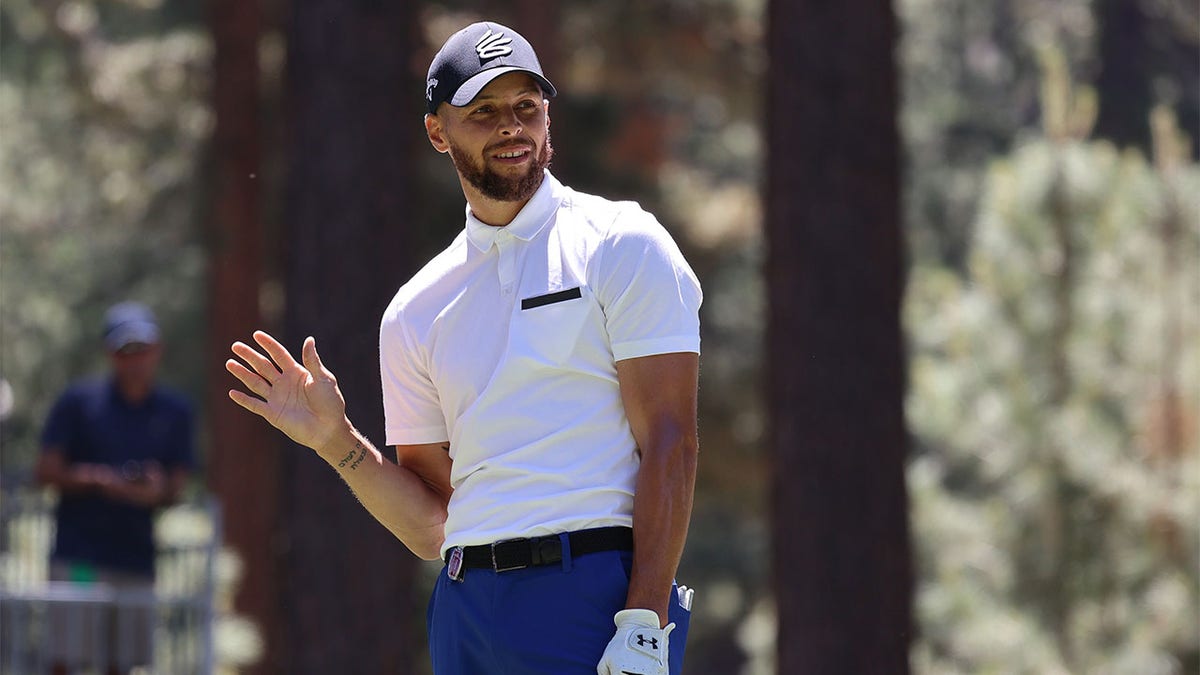 Stephen Curry waves after a tee shot