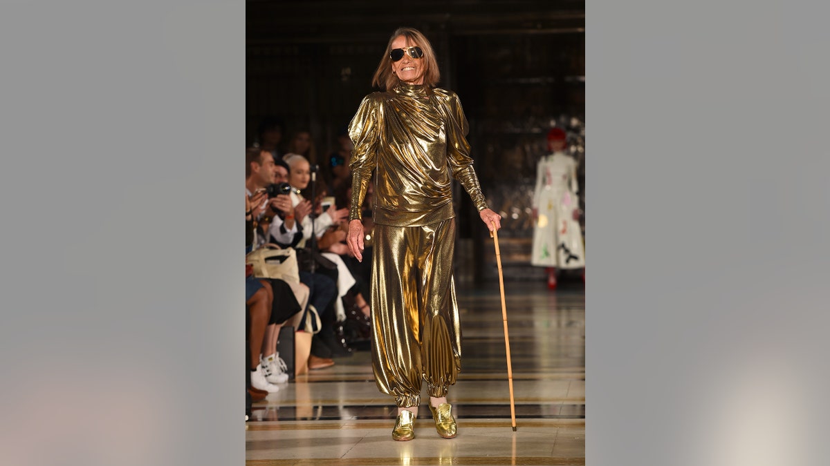 Anita Pallenberg wearing a golden dress and holding a walking stick