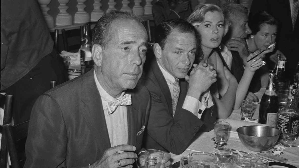 A close-up of Humphrey Bogart sitting next to Frank Sinatra