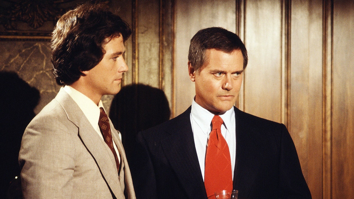 Patrick Duffy in a tan suit next to Larry Hagman in a dark blazer and red tie