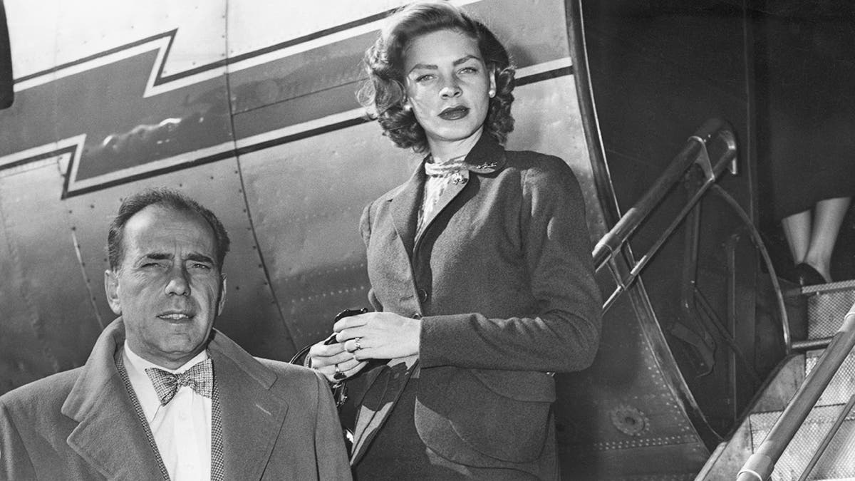 Humphrey Bogart posing next to a plane and his wife Lauren Bacall in formal wear