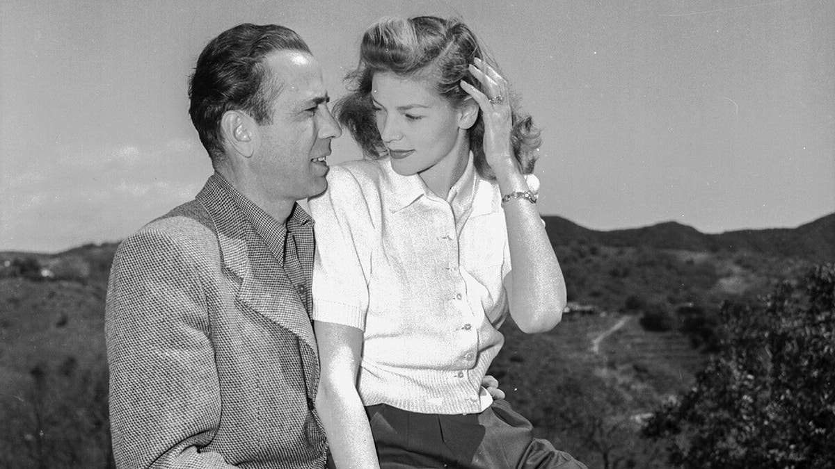 Lauren Bacall wearing a white shirt as she sits on Humphrey Bogarts lap