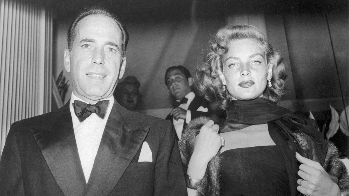 Lauren Bacall in a glamorous dark dress next to Humphrey Bogart in a bow-tie