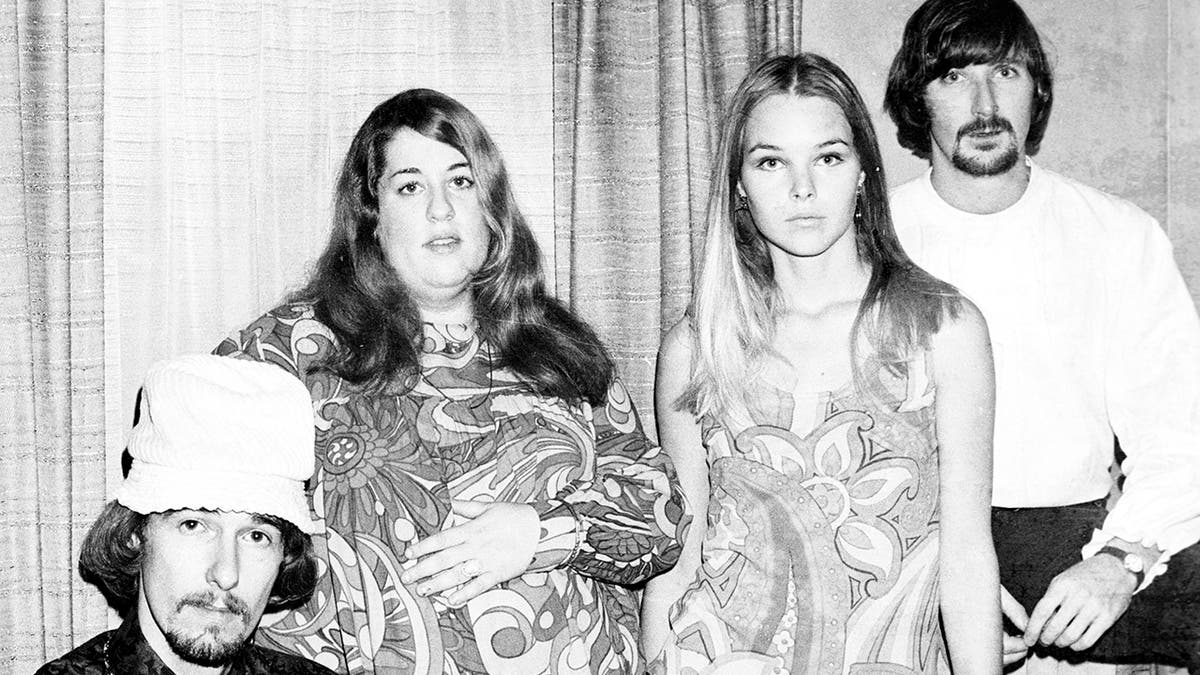 A black and white photo of the mamas and the papas wearing 60s style clothing