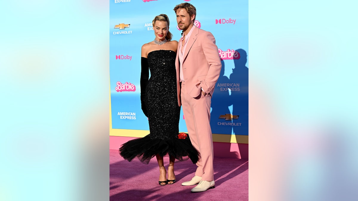 Margot Robbie wearing a vintage black Barbie dress posing next to Ryan Gosling in a pink suit