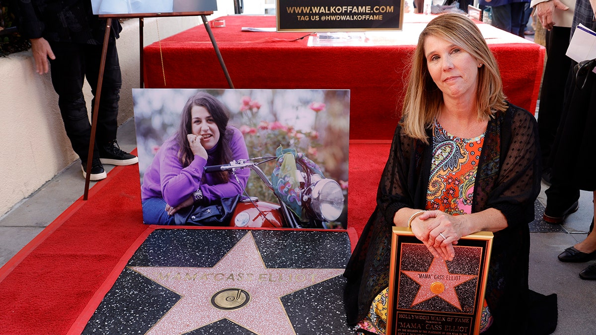 Owen Vanessa leaning on the floor and holding a star next to her mothers portrait
